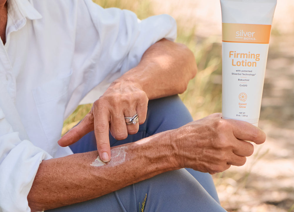 Woman holding a lotion bottle and rubbing lotion with her finger on her arm