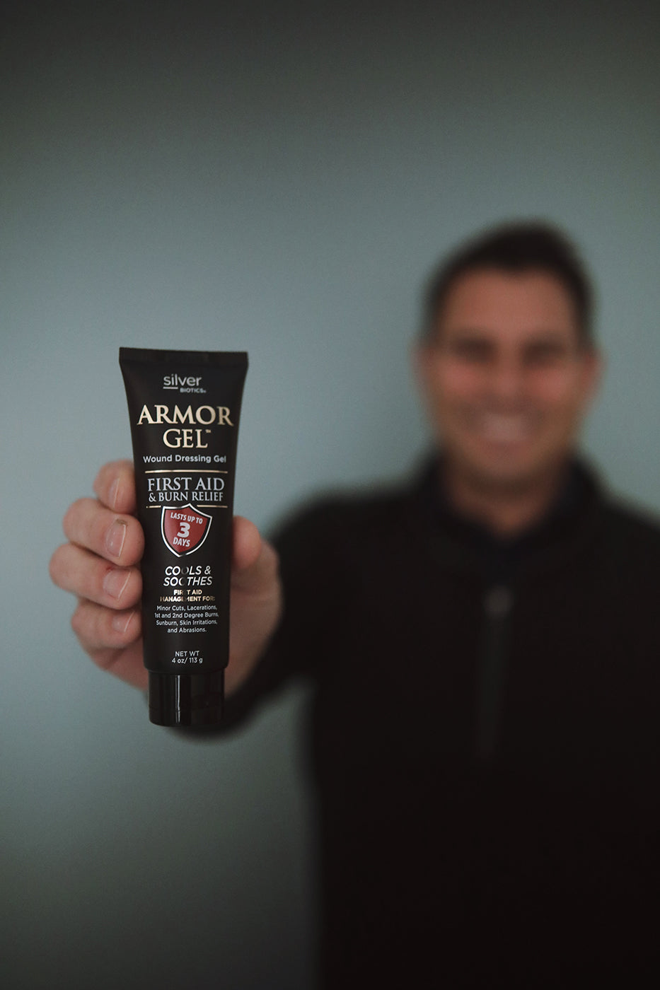 Person holding a tube of Armor Gel against a blurred background