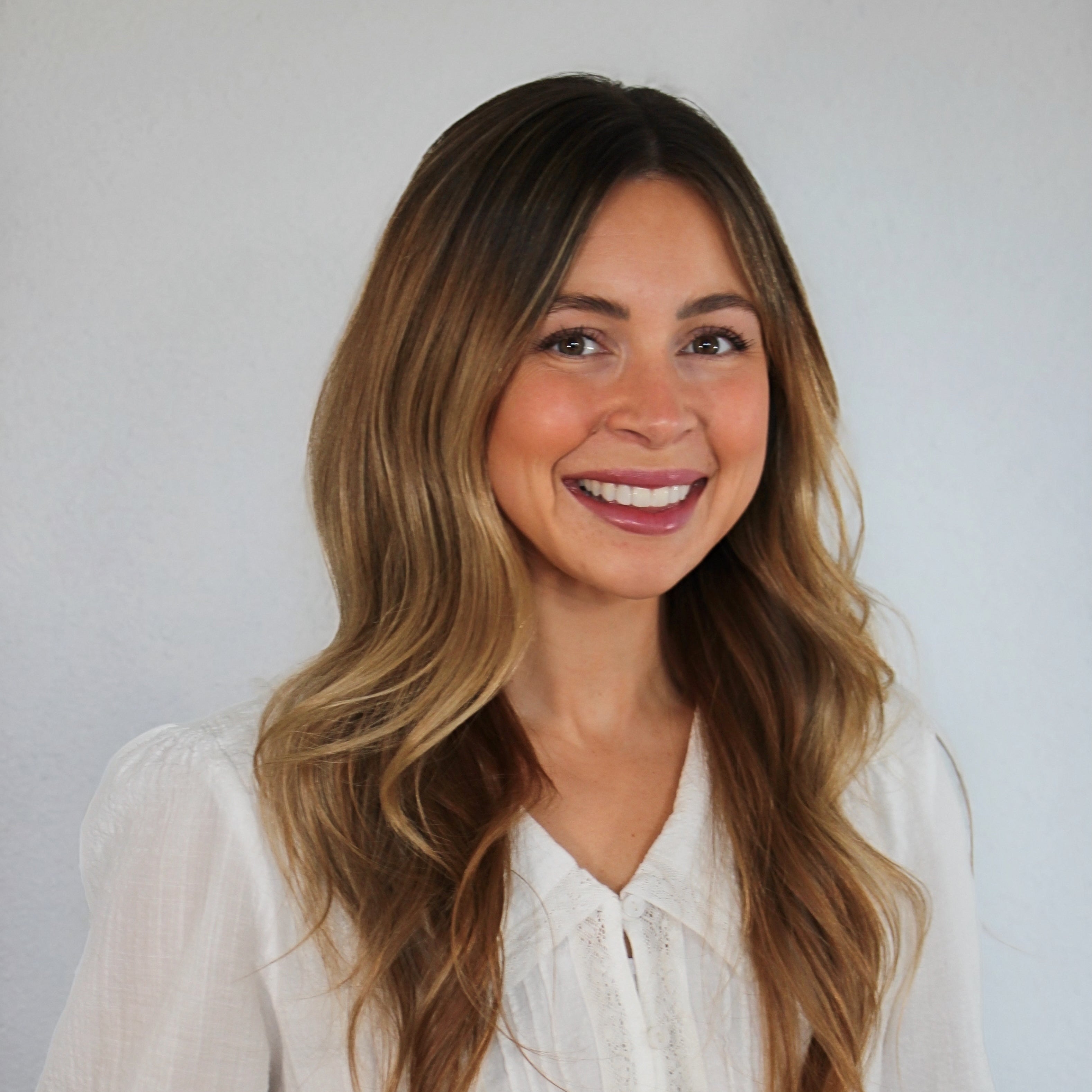 Woman wearing a white blouse against a plain background