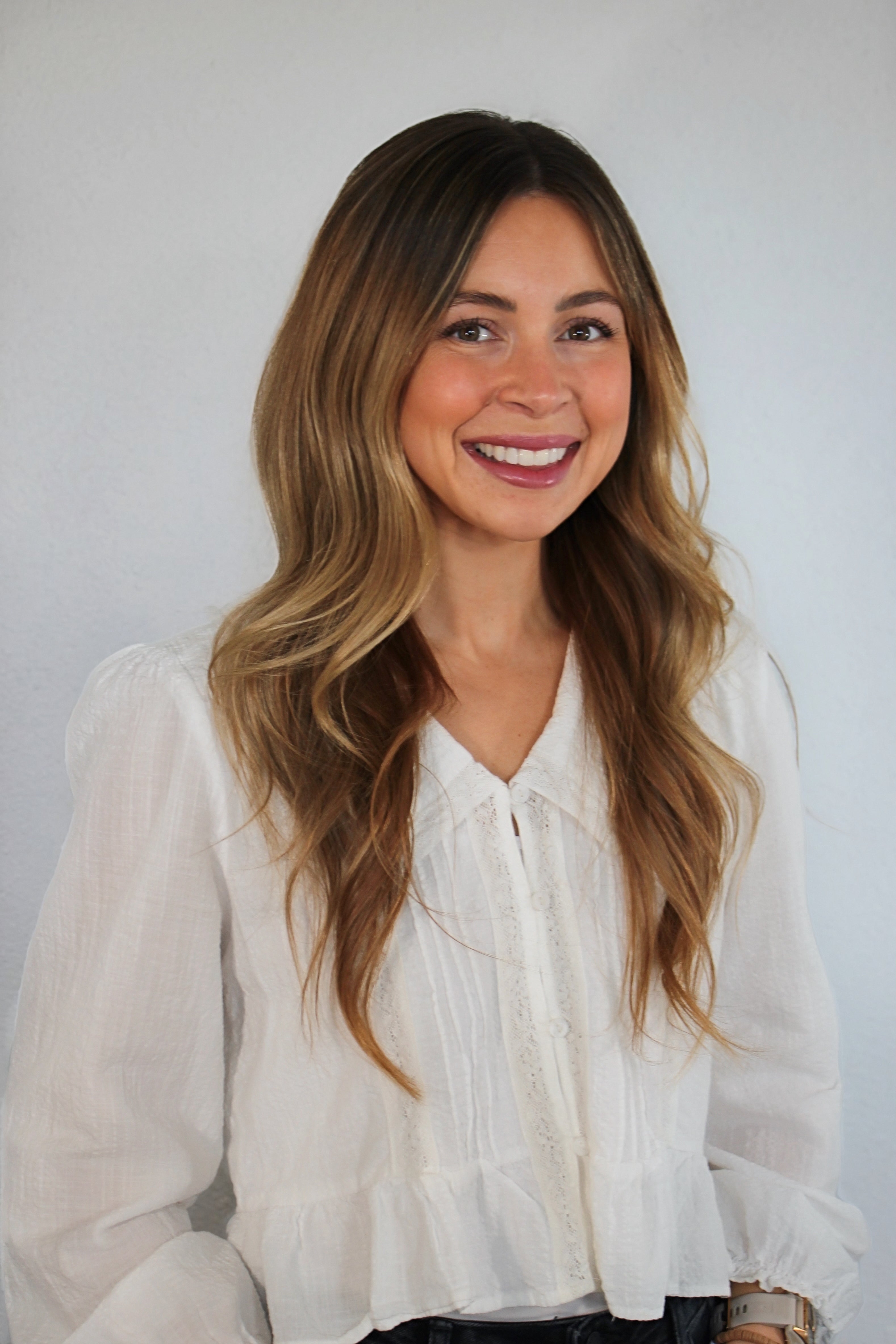 Woman wearing a white blouse against a plain background