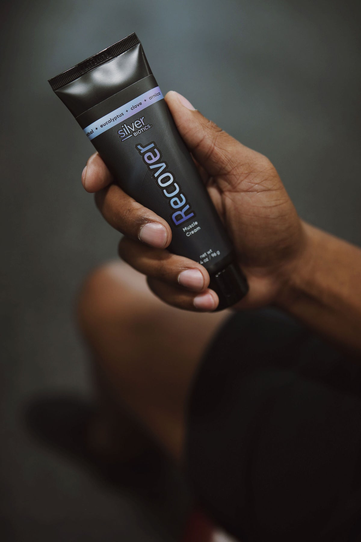 Hand holding a 'Recover' product with a dark background