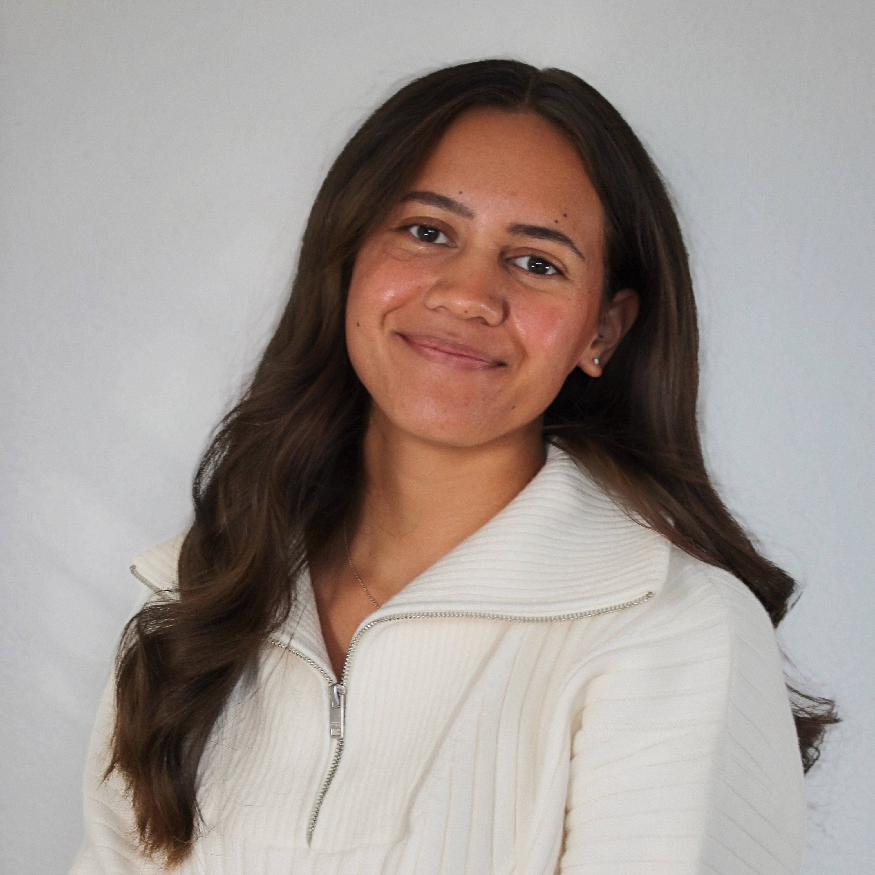 Woman wearing a white sweater against a plain background