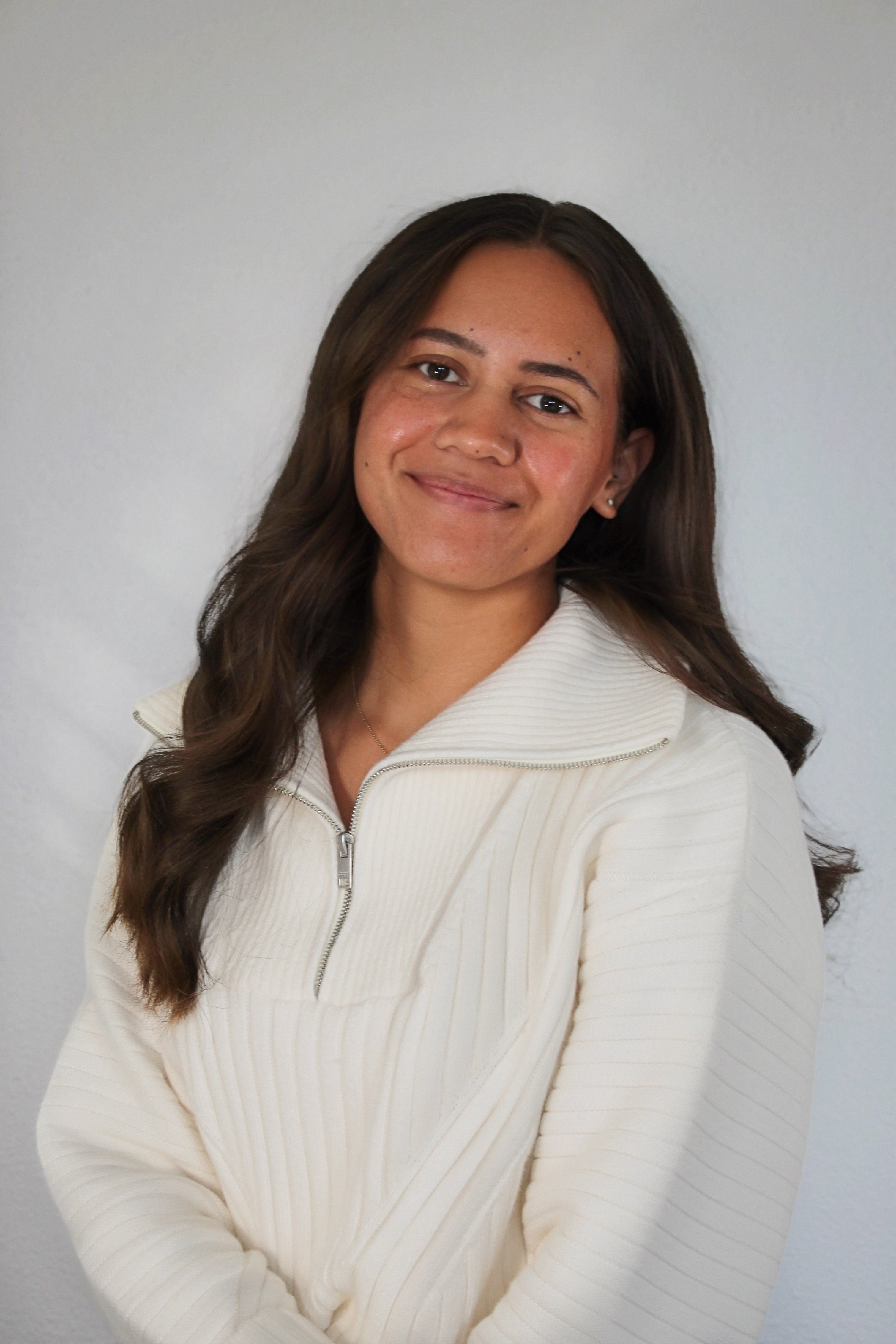Woman wearing a white sweater against a plain background